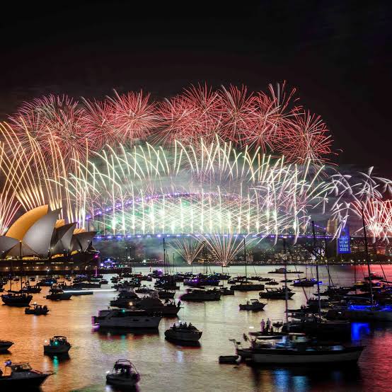Fireworks lighting up the night sky over a harbour on New Year's Eve